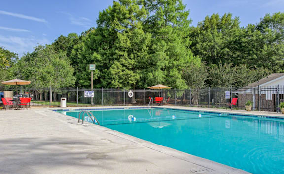 A swimming pool surrounded by trees and a fence with a signboard at Gates at Summerville, Summerville, SC, South Carolina