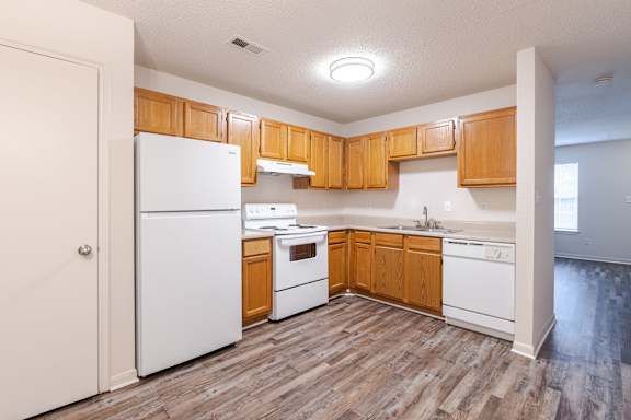 A kitchen with wooden cabinets and white appliances at The Village at England Run, Fredericksburg, VA