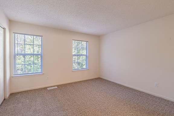 A room with two windows and carpeted floor at The Village at England Run, Fredericksburg, VA