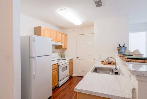 A kitchen with a white refrigerator, sink, and cabinets.at Woodwind Villa Apartments, Virginia, 22191