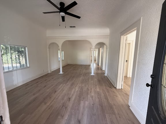 A room with a ceiling fan and arched doorways.