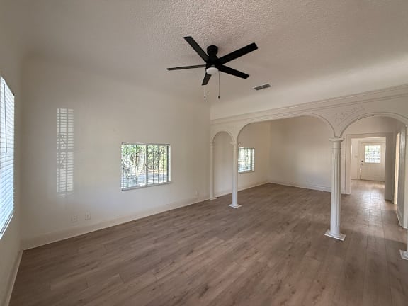 A room with a ceiling fan and wooden flooring.