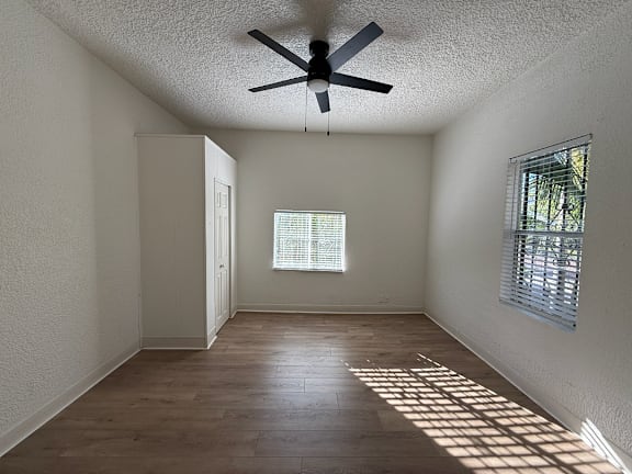 A room with a ceiling fan and wooden flooring.