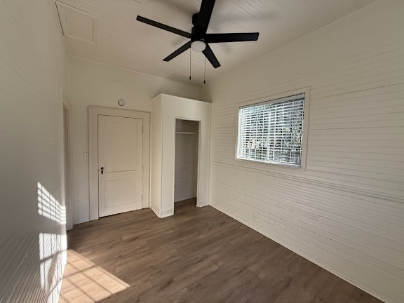 A room with a ceiling fan and a window with blinds.