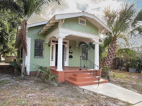 A green house with a white door and black railings.