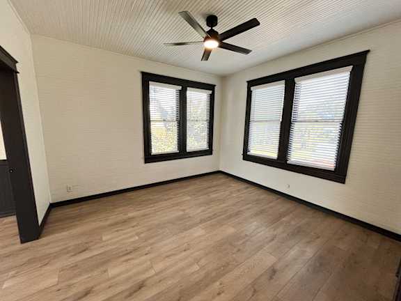 A room with a ceiling fan and wooden flooring.