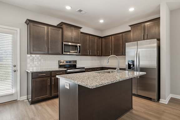 A kitchen with dark brown cabinets and a granite countertop.