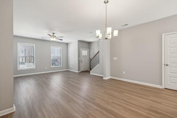 A spacious room with a staircase and a chandelier.