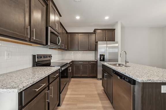 A kitchen with dark brown cabinets and a granite countertop.