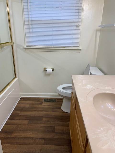 A bathroom with a toilet, sink, and window.