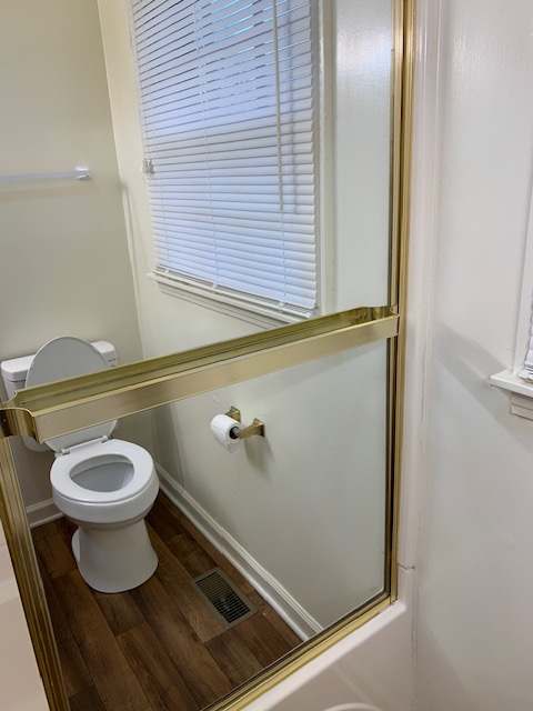 A toilet is installed in a bathroom with a wooden floor.