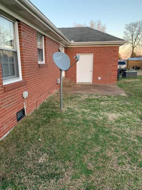 A red brick house with a satellite dish on the roof.