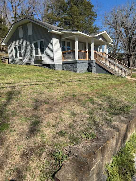 A house with a grey roof and white walls is situated on a steep hill.