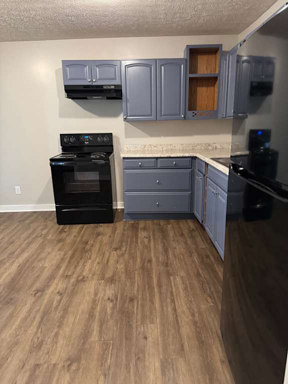 A kitchen with a black oven and wooden floors.