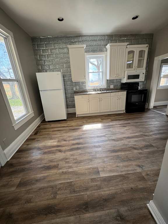 A kitchen with wooden floors and white cabinets.
