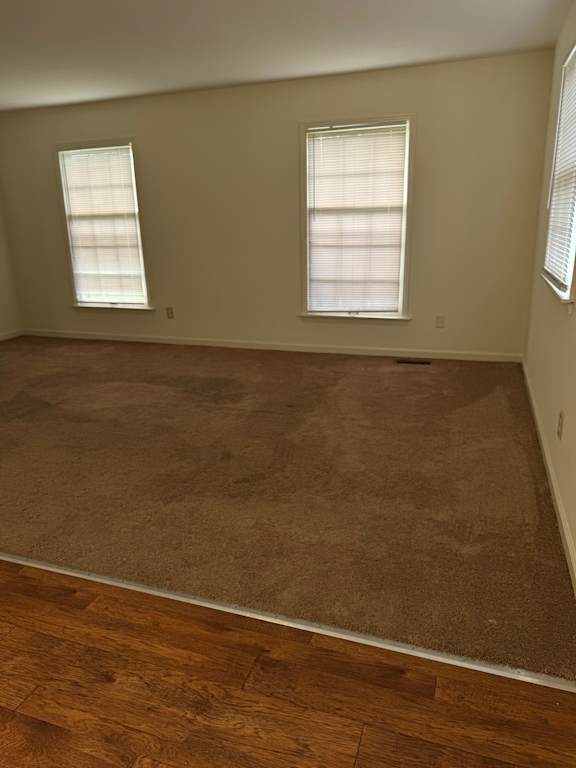 A room with two windows and a wooden floor.