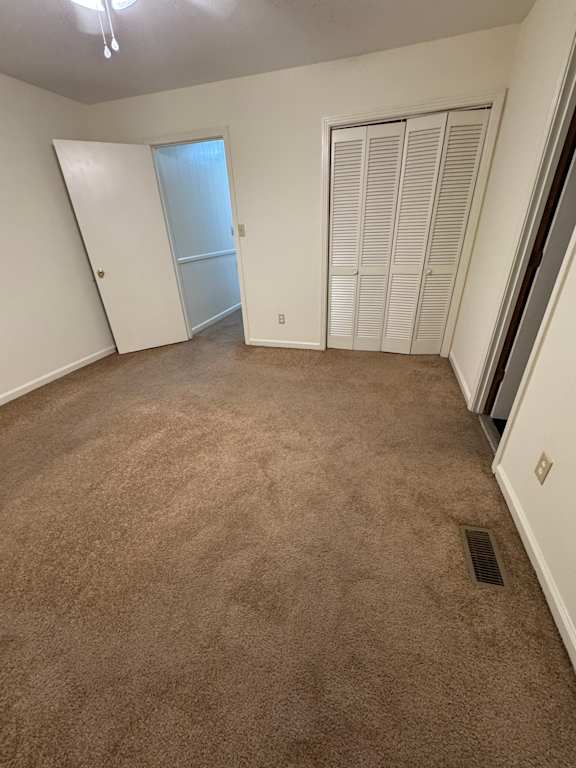 A white air vent and window in a room with brown walls.