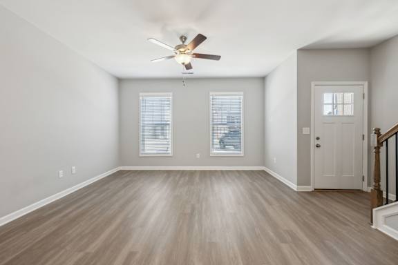 A room with a ceiling fan and wooden flooring.