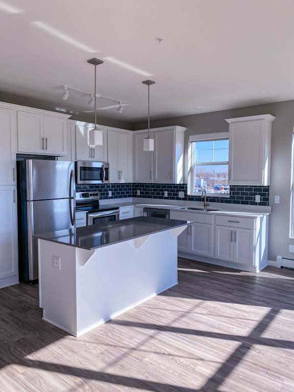 A kitchen with a refrigerator, microwave, and oven.