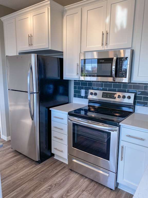 A kitchen with a stainless steel refrigerator, oven, and microwave.