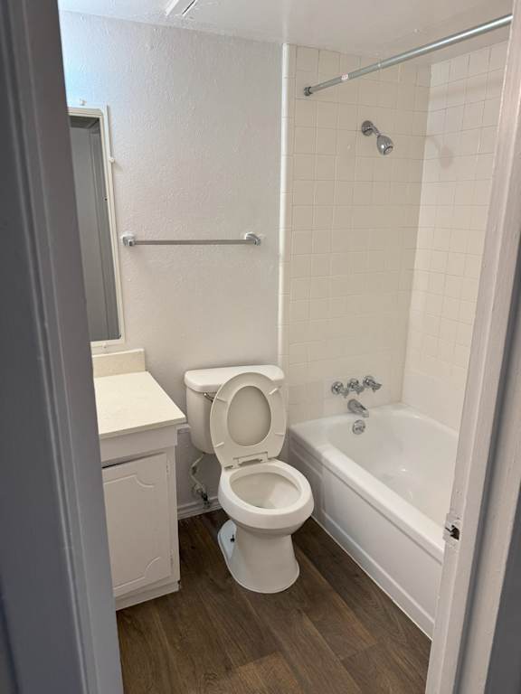 A white toilet sits in a bathroom next to a bathtub.
