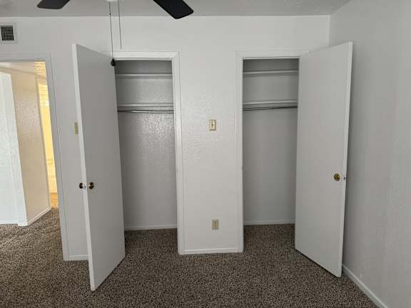 A room with a carpeted floor and three white doors.