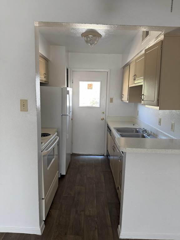 A kitchen with white appliances and a white sink.