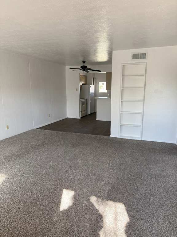 A room with a ceiling fan and a door leading to another room.