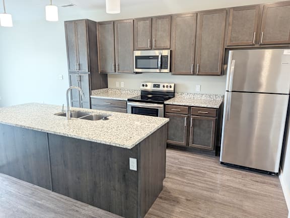 A kitchen with a granite countertop and stainless steel appliances.