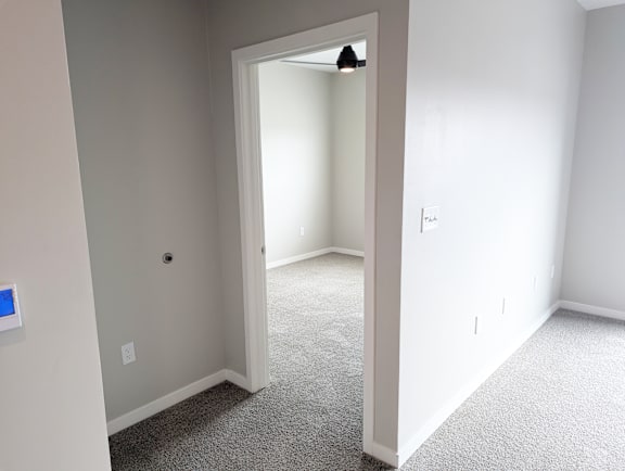 A room with a carpeted floor and a doorway leading to another room.