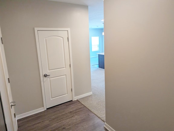 Bedroom entry area with carpet flooring, white doors and closet access at Heartland Flats North Platte.