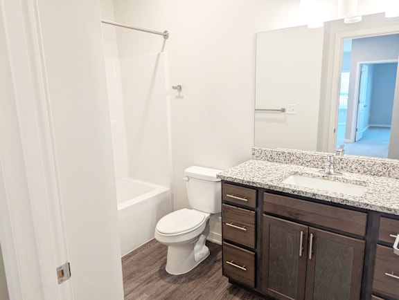 Bathroom with vanity, sink, mirror, toilet and vinyl flooring at Heartland Flats North Platte.