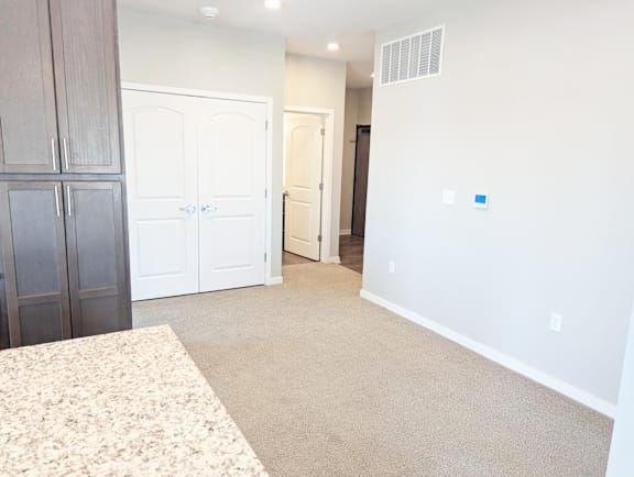 Entry hallway with carpet flooring, white doors and access to the living space at Heartland Flats North Platte.