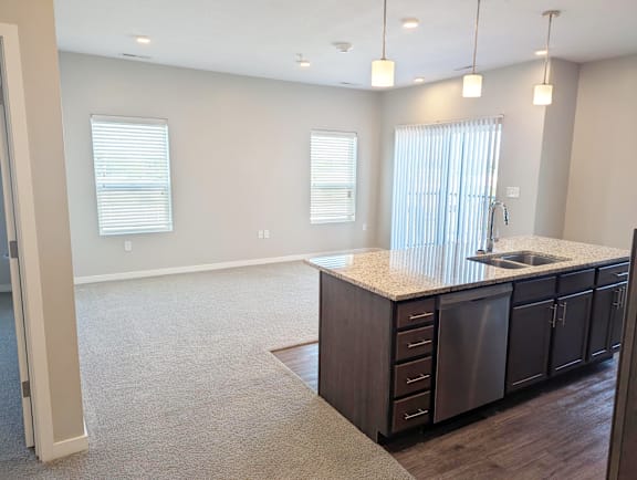 Living area with carpet flooring, open layout and large windows at Heartland Flats North Platte.