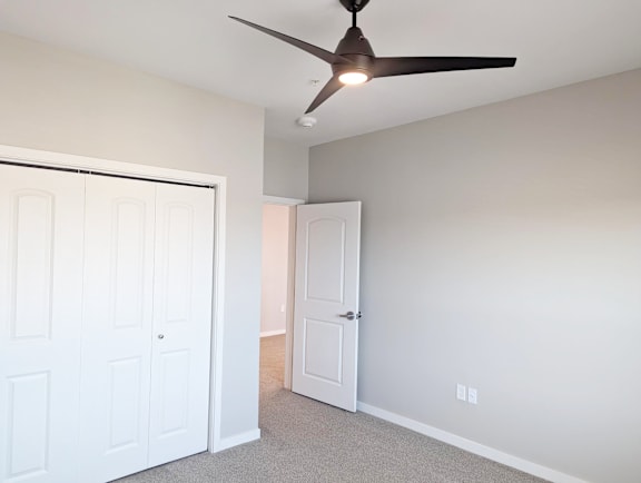 A room with a ceiling fan and two doors.