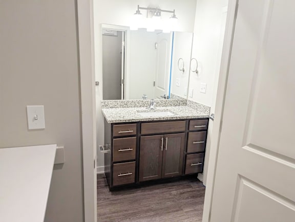 Bathroom with double vanity, mirrors, lighting and vinyl flooring at Heartland Flats North Platte.