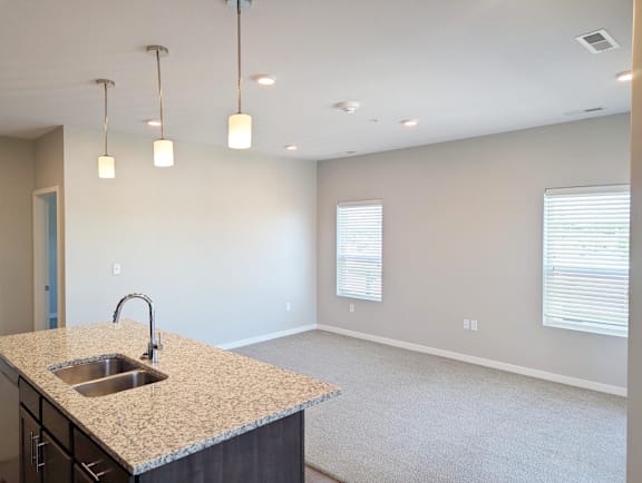 Kitchen view showing island, sink, pendant lighting and open connection to the living space at Heartland Flats North Platte.