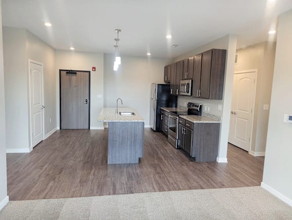 A kitchen with a refrigerator, microwave, and oven.