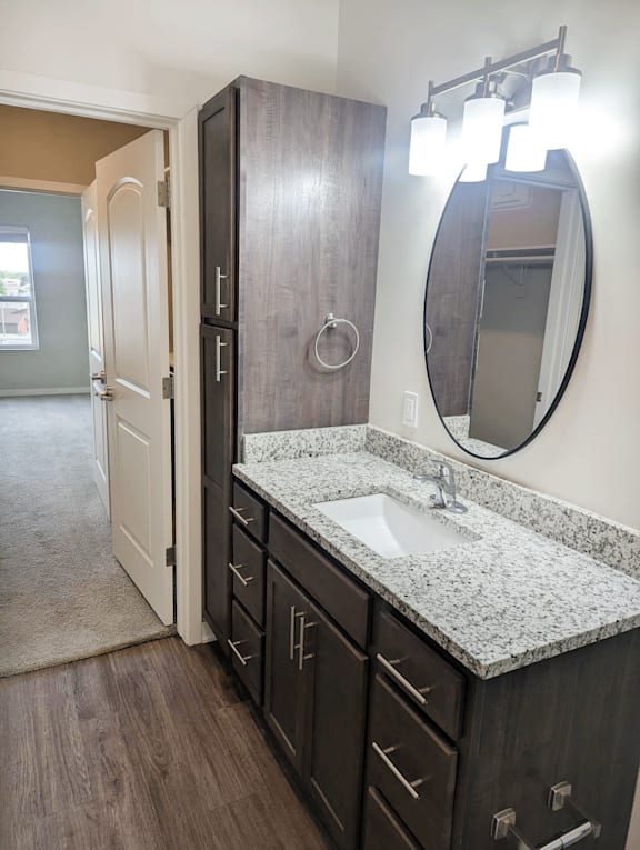 A bathroom with a sink, mirror, and cabinets.
