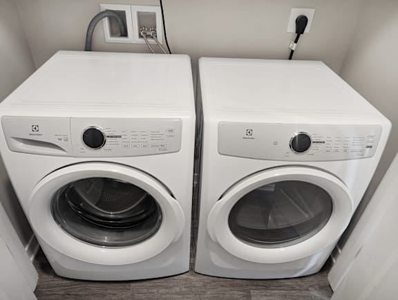 Two white front loading washing machines in a laundry room.