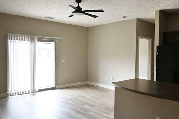 A room with a ceiling fan and a window with blinds.