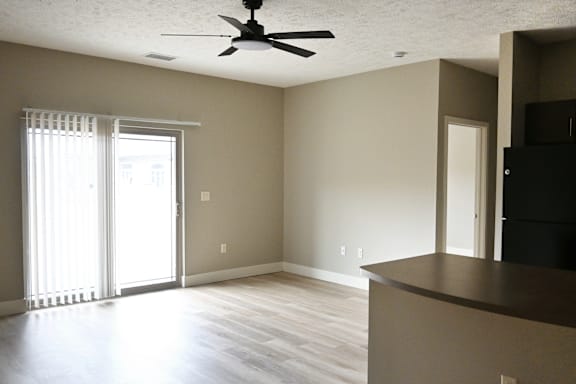 A room with a ceiling fan and a window with blinds.