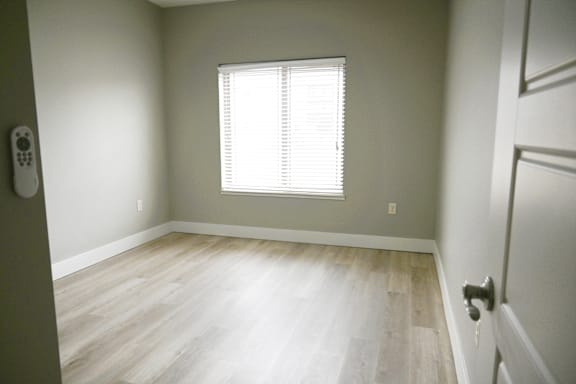A room with a window and wooden flooring.