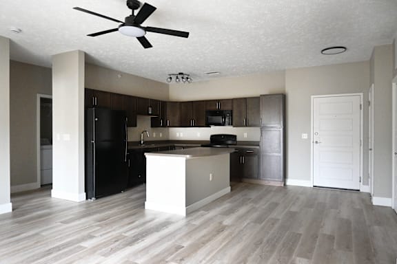 A kitchen with a black refrigerator and a white island.