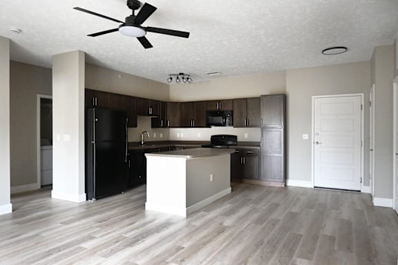 A kitchen with a black refrigerator and a white island.
