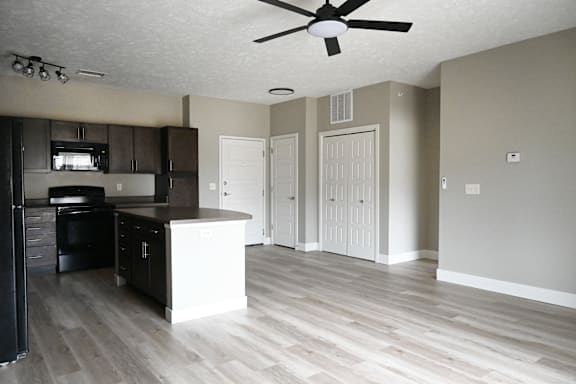 A kitchen with a black refrigerator and white cabinets.