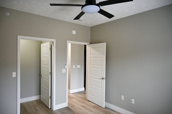 A room with a ceiling fan and two doors.