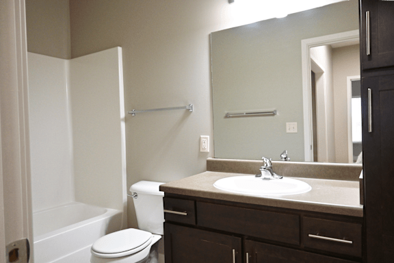 A bathroom with a toilet, sink, and mirror.