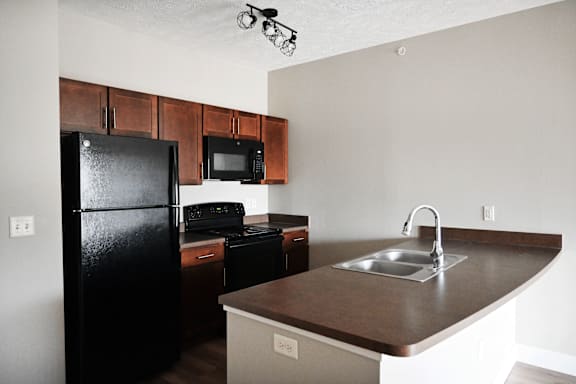 A kitchen with black appliances and brown countertops.