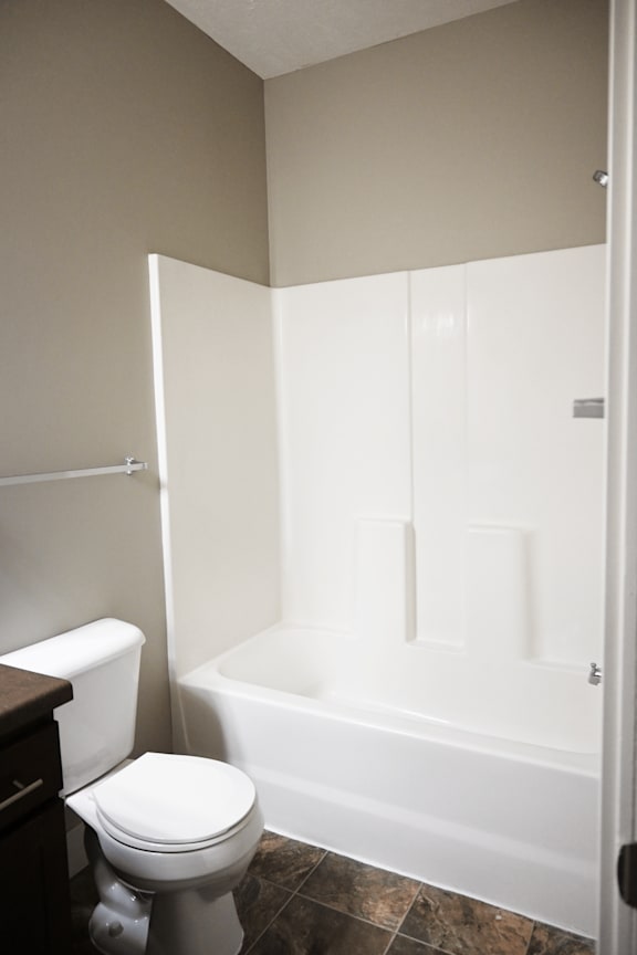 A white toilet sits next to a white bathtub in a bathroom.